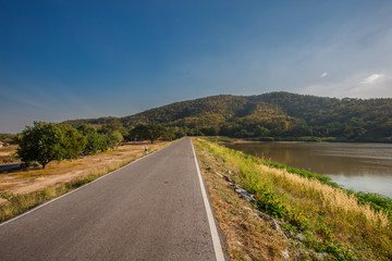 The blurred panoramic nature background of sunlight hitting the lake's surface, grass and wind blowing all the time along the large mountains, ecological beauty and fresh air.