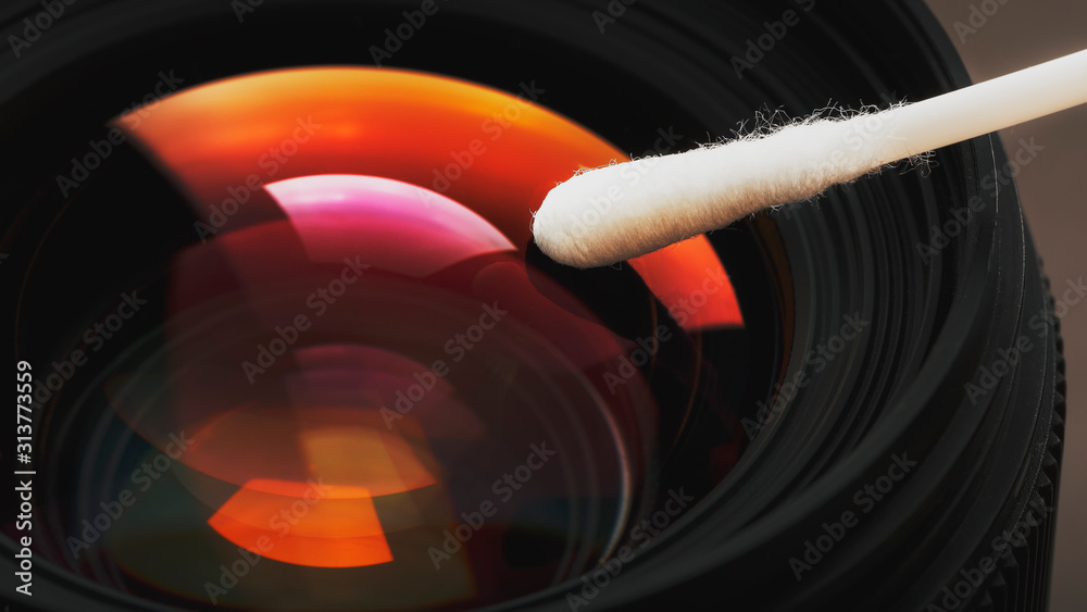 Poster gentle cleaning with a cotton swab camera lens with a beautiful optical block close-up.