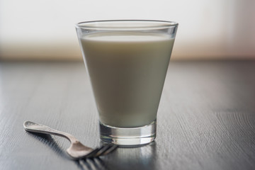 Latte coffee in a tall glass, against the window. Photographed close-up.