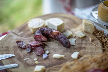 Detailed view of a hand slicing homemade pork chorizo and cheese on wooden table