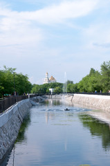 Fototapeta premium Russia, Blagoveshchensk, July 2019: fountain on the pond in the Park of friendship in the city of Blagoveshchensk in the summer, in the distance Church