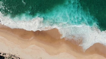 Aerial view of drone flying above beautiful beach with views of ocean waves and water crashing on to sandy beach from top angle - Powered by Adobe