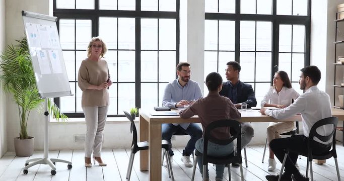 Older business woman manager give flip chart presentation at training