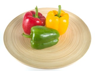  Three colored bell peppers in a white background wooden plate