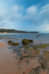 Fototapeta na wymiar Mossy rock formation on the beach coastline.