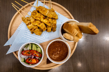 Pork satay - Grilled pork served with peanut sauce or sweet, breads and sour sauce on wooden plate.