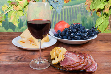 Red wine, cheese, cured pork, fruits against the vine