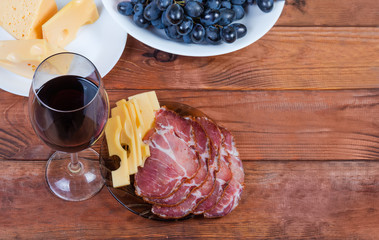 Red wine among the cheese, cured pork, grape, located left