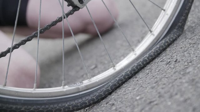 close up of a bicycle flat tire. A cyclist with gloves feeling the tire. pressing the tyre to feel if it is deflated.