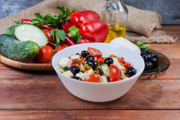 Vegetable salad with mozzarella in bowl against the ingredients