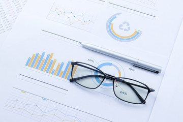glasses and pen on stock chart