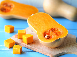 Butternut squash pumpkin cut in half on a wooden chopping board for autumn vegetable harvest.