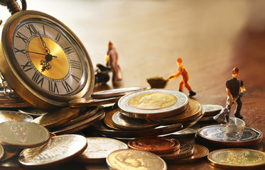 Miniature laborer with piles of coins. The concept of working hours /labor and economic concept..