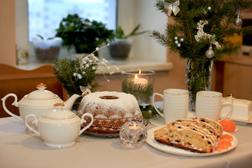 Christmas cupcake with dried fruits from prunes, raisins, dried cherries and nuts on the background of a tea set, Christmas tree branches and a lit candle