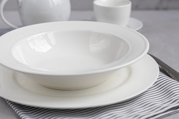 Dining layout. Beautiful serving on a gray linen napkin. A plate for soup or a side dish. Light gray background and white plates.