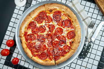 Tasty pizza with salami, onion and parmesan with red sauce on a white background. Italian traditional cuisine. Delicious food flat lay. Top view