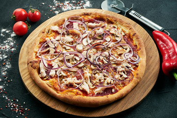 Pizza with a large number of toppings: chicken, onions, mushrooms, cheese and creamy sauce. Pizza in composition with ingredients on a black background