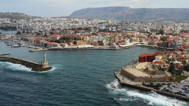 Aerial drone view video of iconic and picturesque Venetian old port of Chania with famous lighthouse and traditional character, Crete island, Greece. Architecture of the Venetian port in Chania.