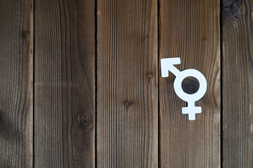male and female symbol for gender equality cut out of paper on a wooden background. space for text
