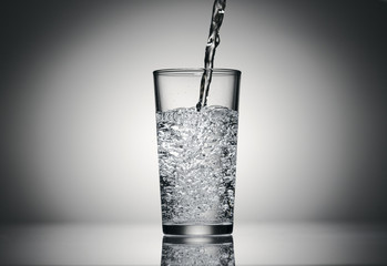pouring sparkling water in a glass on a dark background