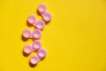 Pink contact lens cases on yellow background