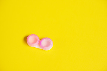 Pink contact lens cases on yellow background