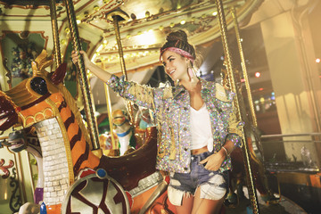 Stylish woman wearing sparkling jacket on the carousel
