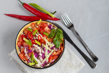 Diet salad made from fresh vegetables. Peking cabbage lilac and green, tomatoes, green onions and chili peppers. Dressed with olive oil.