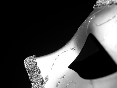 close-up view from the side of a silver carnival mask on a black background