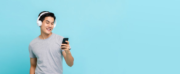 Asian man wearing headphones listening to music from smartphone