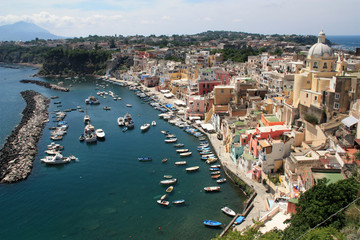 Fototapeta na wymiar Scenic view of the harbor in Corricella on Procida, Golfo di Napoli, Italy, with the vibrantly colorful houses painted in different pastel shades