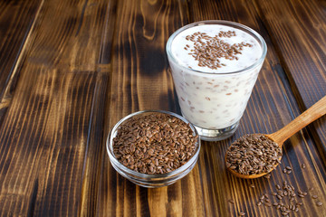 Yogurt or kefir with flax seeds in the glass on the brown wooden  background. Copy space.
