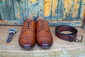 A groom's accessories by an old wooden door
