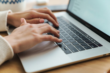 Fototapeta na wymiar Cropped photo of young caucasian woman typing on laptop