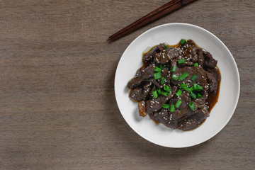 top view of stir fried beef with teriyaki sauce in a ceramic dish on wooden table. asian homemade style food concept.