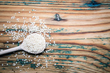 Organic natural sesame seeds and spoon on old wooden table