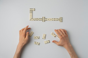close up person hand holding domino pieces and play the game on the white table