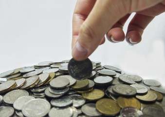 Man's hand put money coins to multi-currency pile of coins. Financial, Money saving concept.