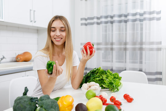 Young housewife estimating bell peppers she has bought among other various greengrocery