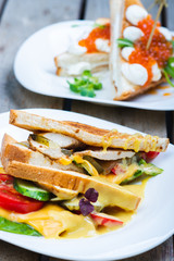 Classic breakfast, hot sandwiches with cheese, vegetables and chicken on a wooden table.
