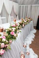 The main table decorated with roses at a wedding reception
