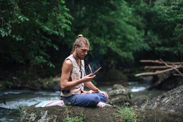 Yoga practice and meditation in nature. Man practicing near river