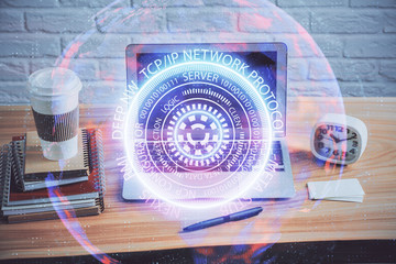 Computer on desktop in office with technology theme hologram. Multi exposure. Tech concept.