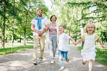 Big happy family with two kids walk in the park.