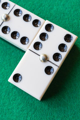 Top view of two domino pieces on green mat in vertical