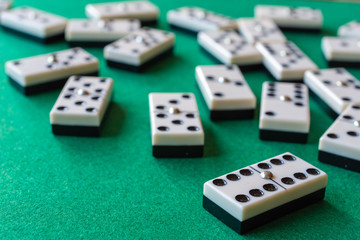 Top view of domino pieces, the six double focused, the rest out of focus, on horizontal green mat