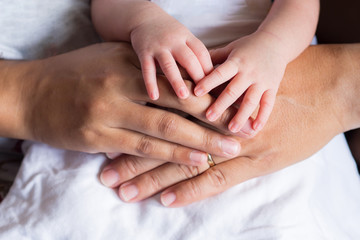 Close-up of newborn hands placed on mother and father hands on white cloth. Happiness parents. Love of family concept. Space for text