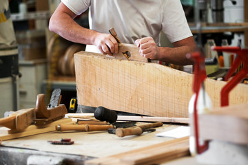 Carpenter planing a block of wood to in workshop