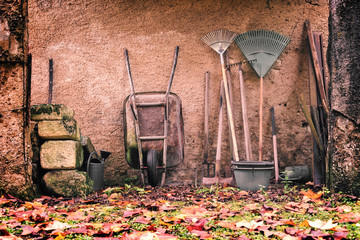 Rustic garden tools against a wall in autumn, vintage process