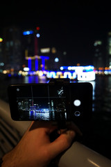 Hand with smartphone making picture of Dubai Marina skyline.